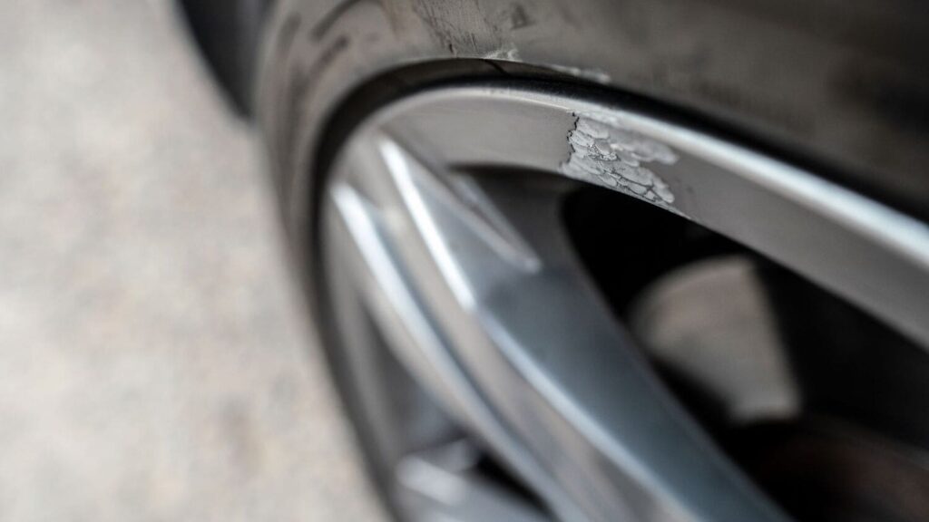 Close-up of a scratched and bent alloy wheel needing repair